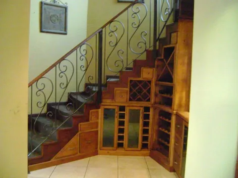 Bodega de vinos bajo la escalera con barandal de herrería