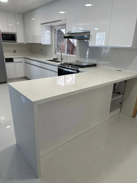 Cocina blanca alto brillo con península de cuarzo en cascada