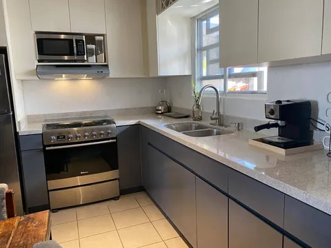 Cocina en L gris y blanco con nicho para microondas y vinera