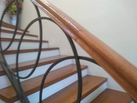 Escalera con peldaños y pasamanos de madera y barandal de herrería