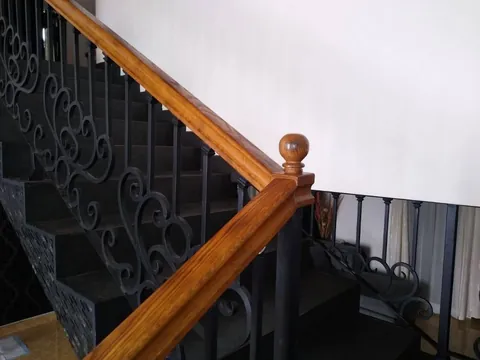Barandal forjado con pasamanos de madera en escalera