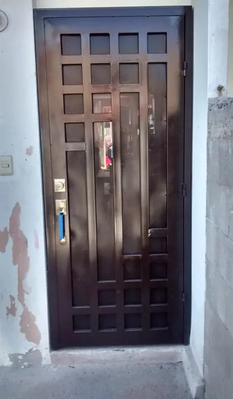 Puerta principal de herrería con reja cuadriculada