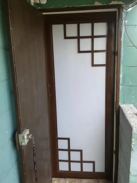 Puerta de herrería con diseño geométrico y vidrio