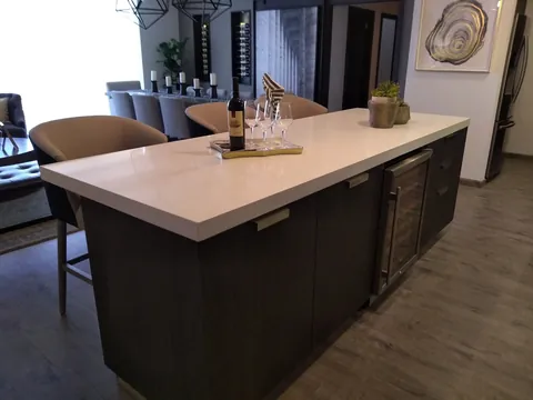 Isla en madera oscura con cubierta blanca y vinoteca integrada